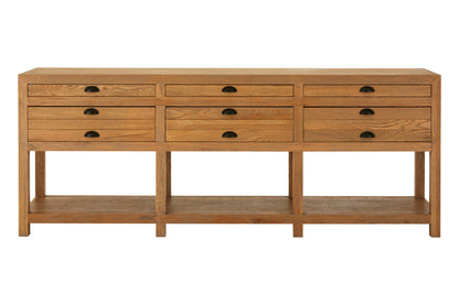A wooden console table with six drawers arranged in two columns of three, featuring a lower open shelf and dark metal oval handles, shown against a plain white background.