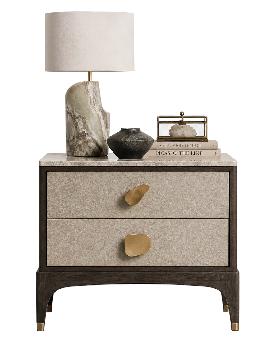 Beige nightstand with gold accents featuring a lamp and decorative items on a white background