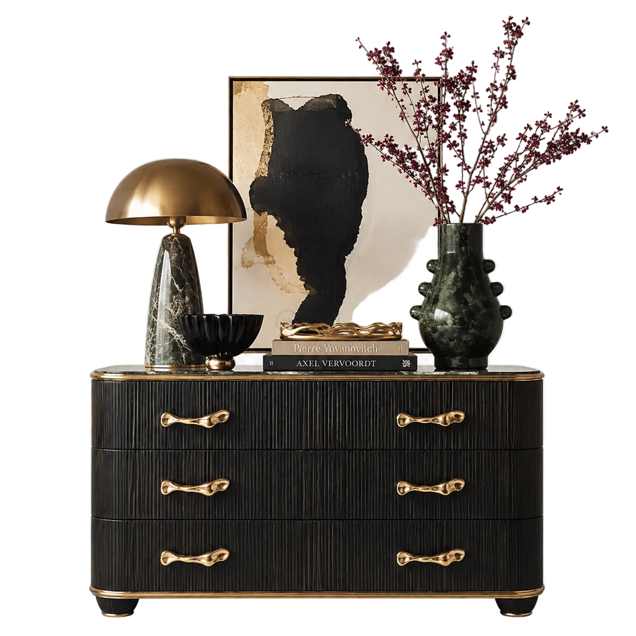 Decorative black dresser with gold handles, lamp, books, and vase on a white background